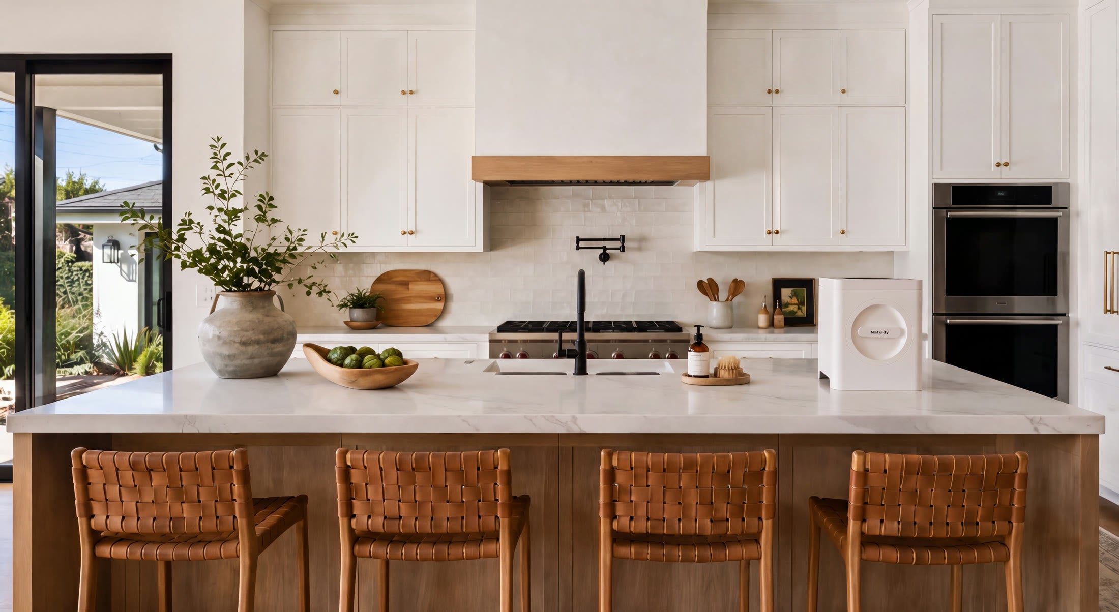 Natridy Electric Composter on a white island kitchen with woven leather stools.